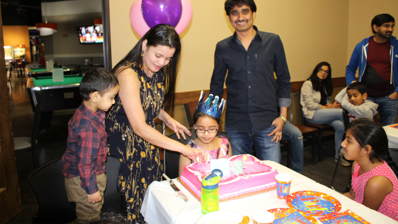 Parents cutting birthday cake for kids